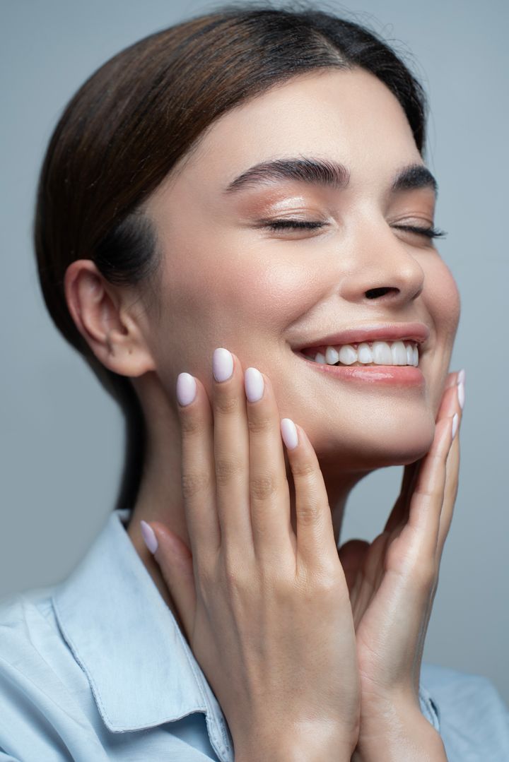 Paciente sorrindo, com pele radiante, em ambiente clínico elegante
