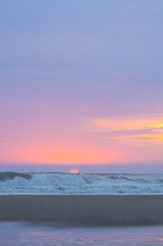 Capture the tranquil beauty of a sunset over ocean waves with pink and blue hues.