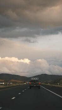 Scenic drive on highway under dramatic cloudy sky during sunset.