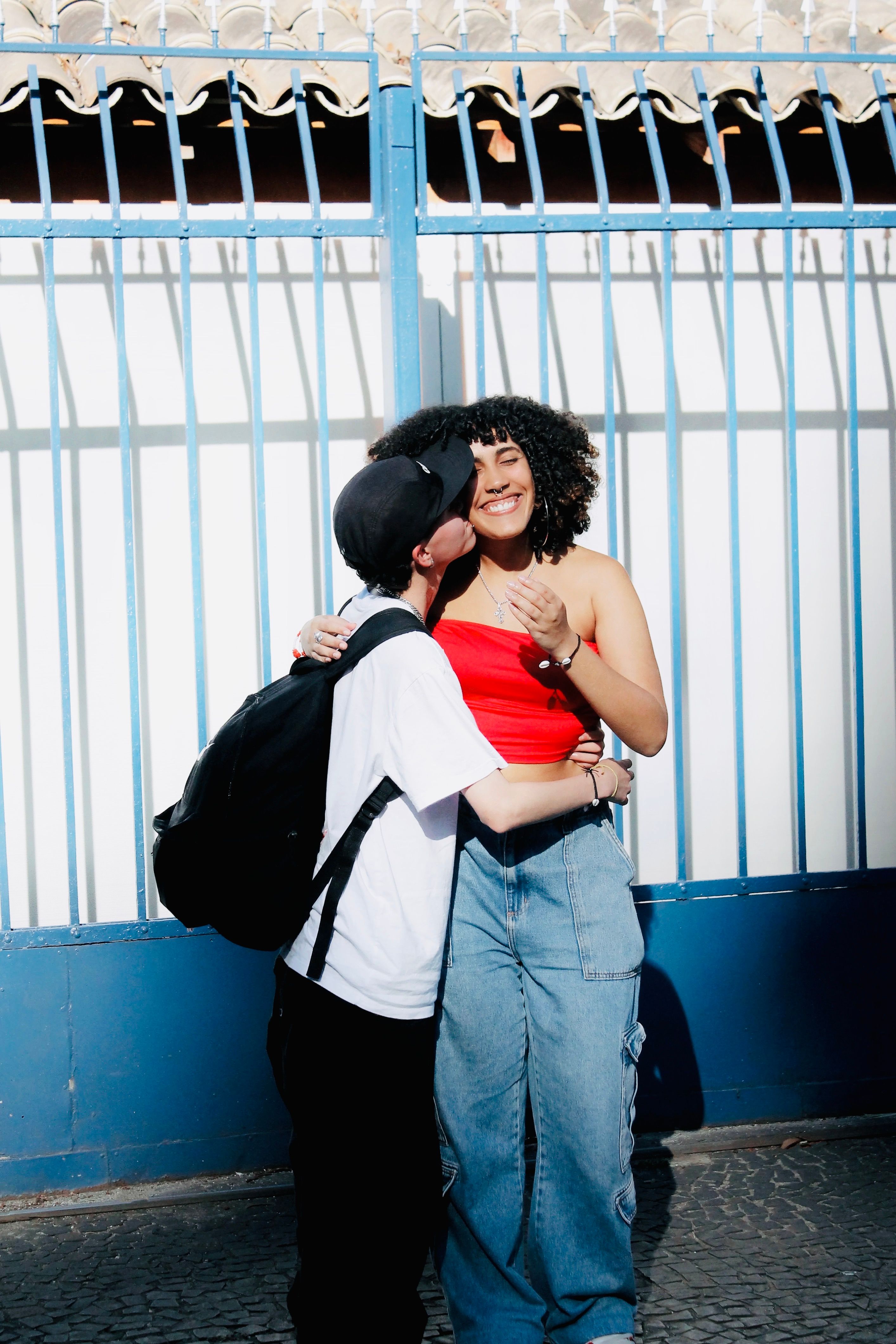 Cheerful Friends Hugging Outdoors by a Gate · Free Stock Photo