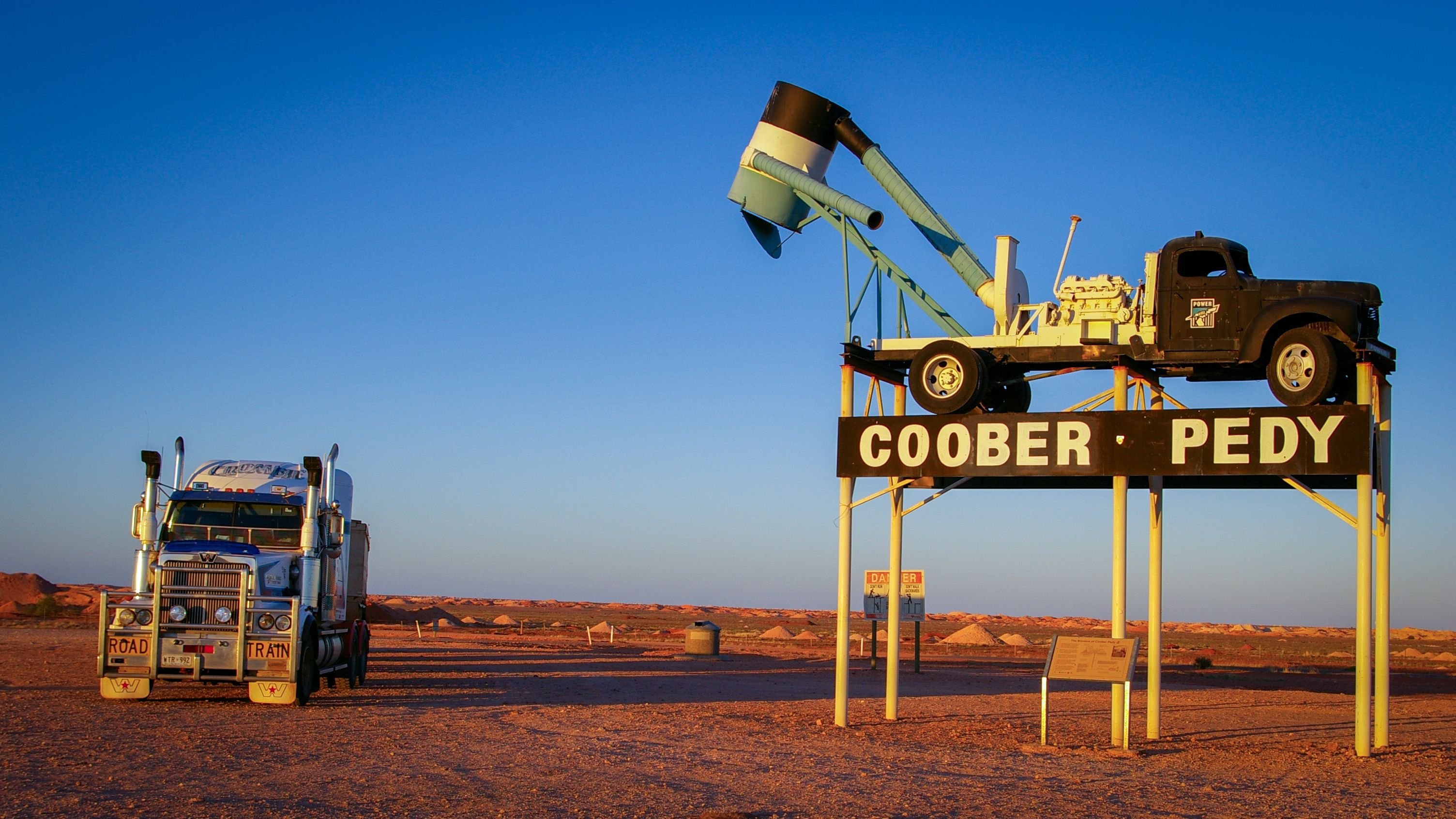 Iconic Coober Pedy landmark featuring a road train truck at sunset in Australia's outback.