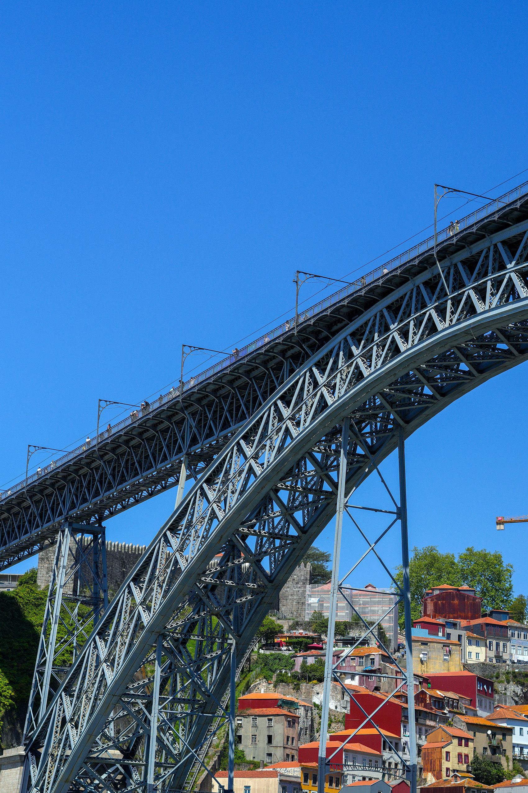 Capture of the iconic Dom Luís I Bridge in Porto, Portugal, under a bright blue sky.