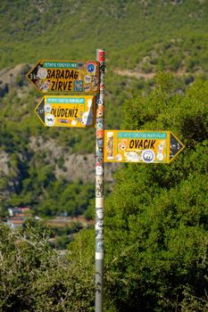 A colorful signpost showing directions to Ovacik, Babadag, and Oludeniz in Turkey's scenic countryside.