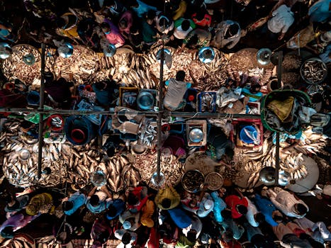 Top-down view of a crowded fish market with vendors and assortments of fish on display.