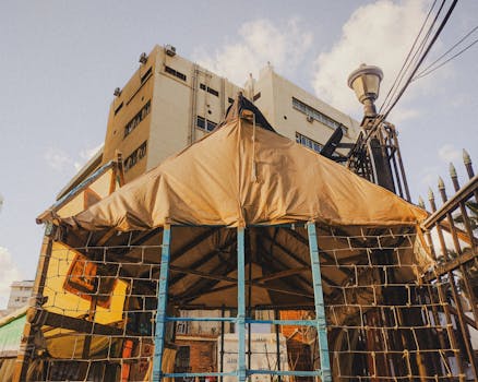A modern urban structure featuring a tent setup beneath a building, capturing architectural symmetry.