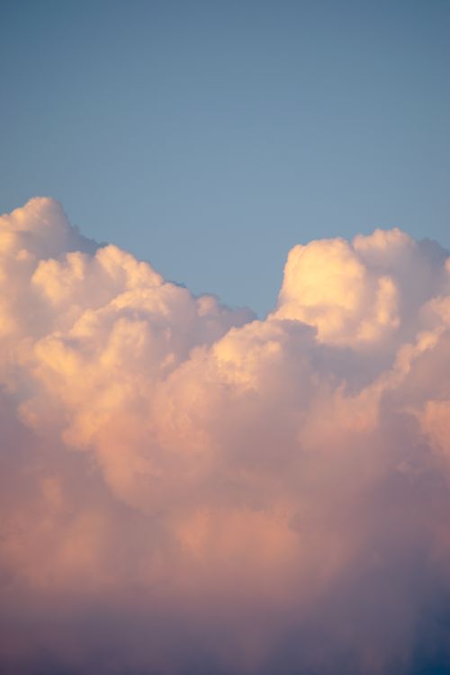 Free Soft pink clouds float against a serene blue sky during sunset, creating a calming and picturesque scene. Stock Photo