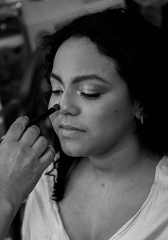 A woman receiving professional makeup with focus on eyes and nose contouring.