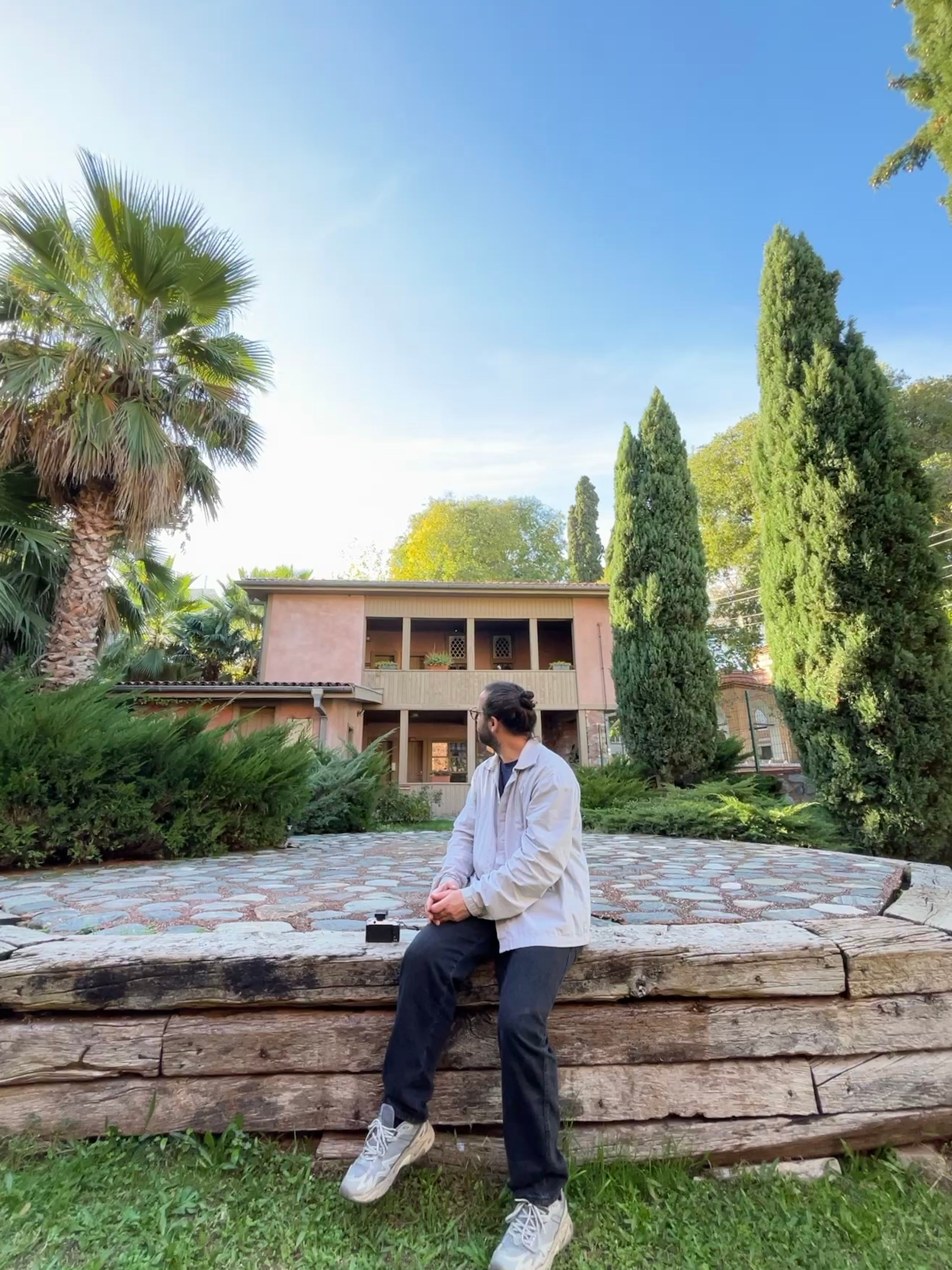 Man Sitting Outdoors in Front of Rustic House · Free Stock Photo