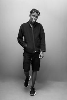 Black and white portrait of a smiling young adult wearing casual attire, conveying a fashionable and relaxed vibe.