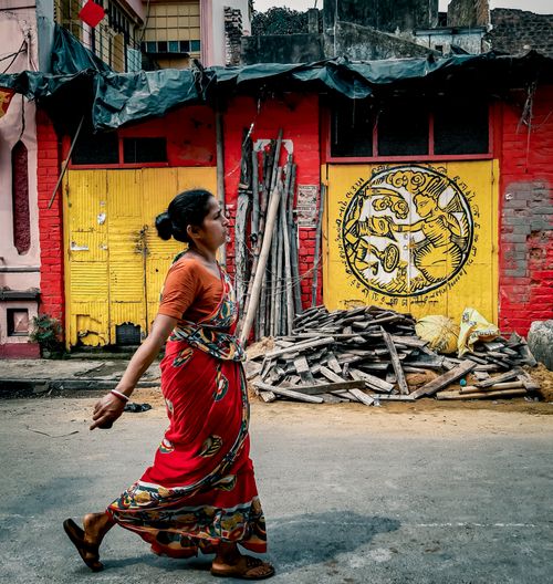 Free An Indian woman in a colorful sari walks past vibrant street art in Kolkata, India. Stock Photo