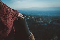 黄昏时分，一名妇女在户外手扶膝盖，欣赏着风景