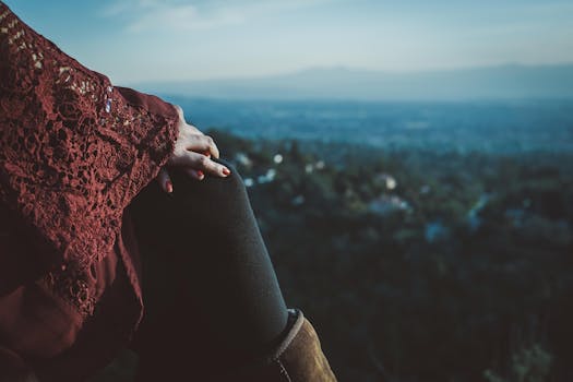 黄昏时分，一名妇女在户外手扶膝盖，欣赏着风景