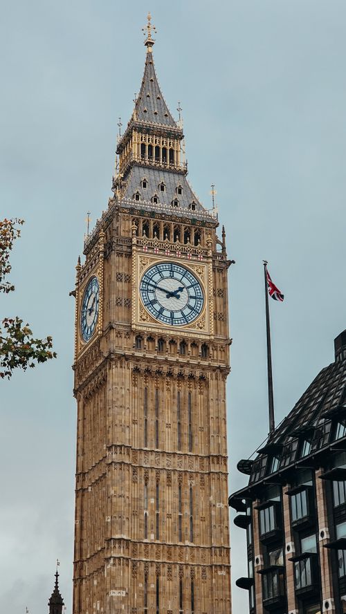 Free A stunning view of Big Ben and the Union Jack flag under a cloudy sky in London. Stock Photo