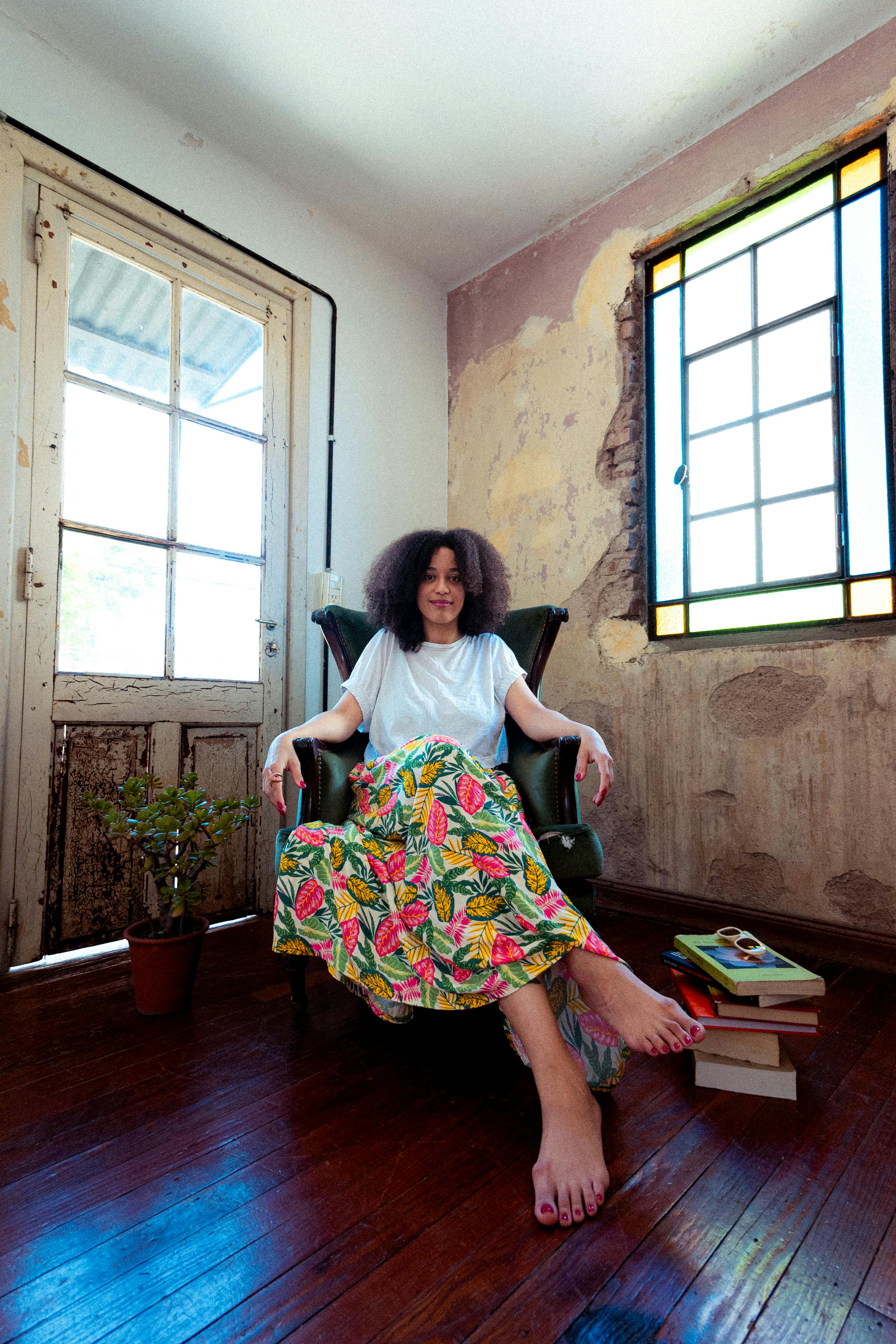 Woman relaxing in a vintage styled room with aged walls and vibrant skirt decoration.