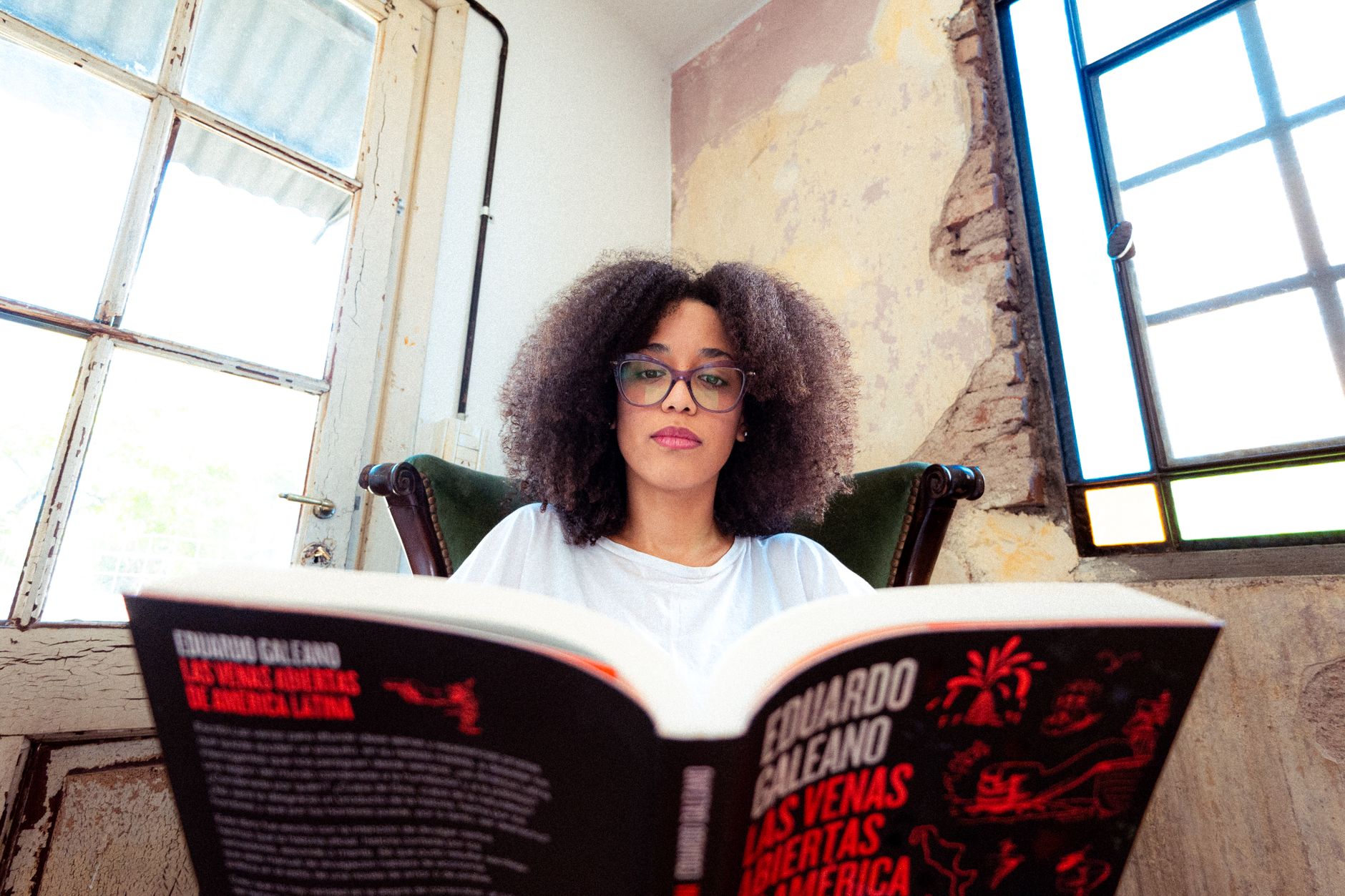 A woman with glasses reads in a vintage interior setting, creating a cozy ambiance.