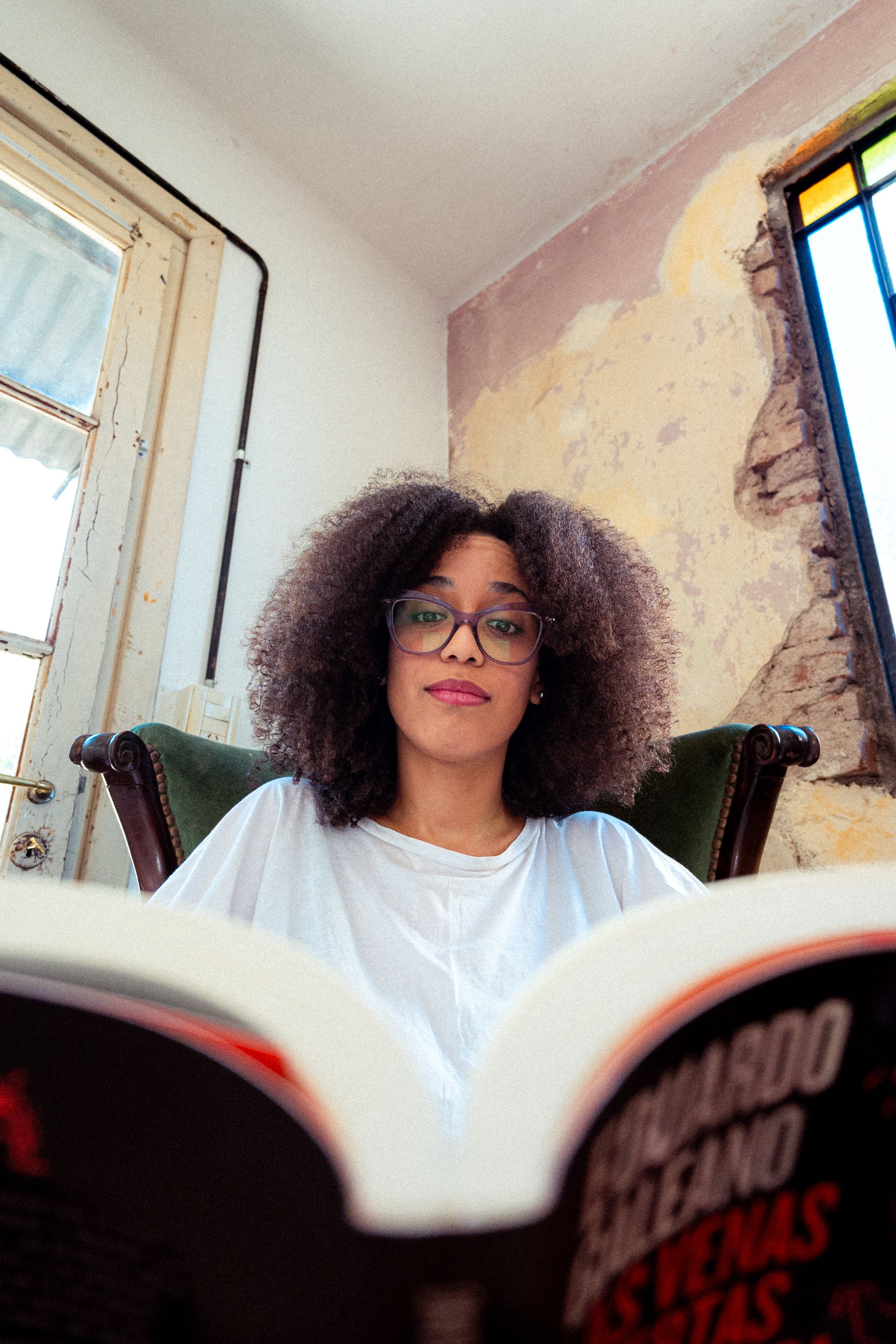Young woman reading a book in a vintage styled room, enjoying leisure time indoors.