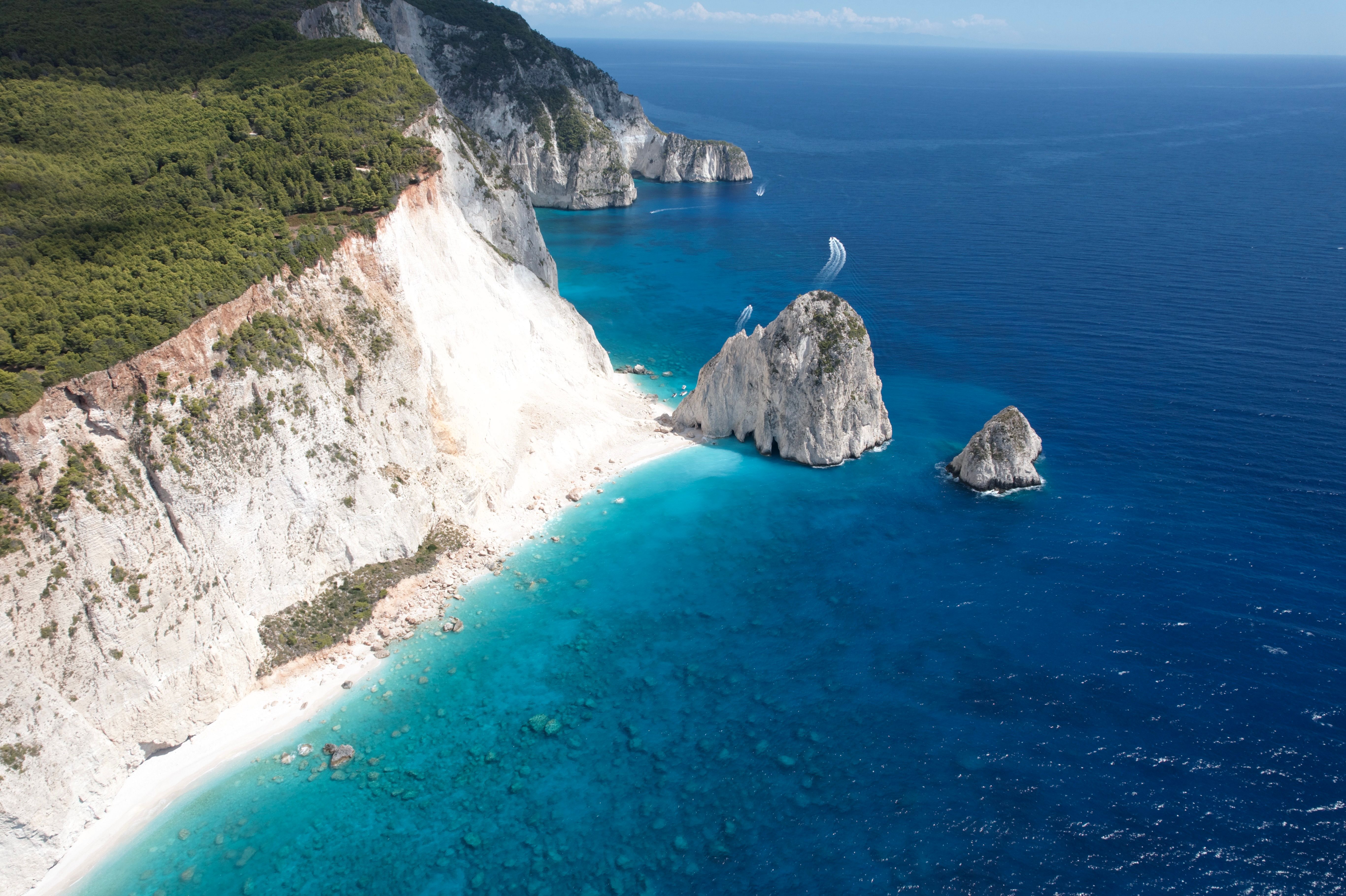 Amazing Santorini 20 Minute Helicopter Ride and Wine Tasting Experience Review 2026 - Breathtaking aerial view of rugged ocean cliffs and turquoise waters in a sunny summer setting.