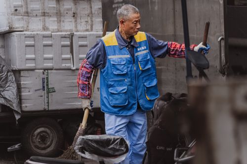 Free An adult male worker wearing a blue vest is engaged in outdoor work involving equipment handling. Stock Photo
