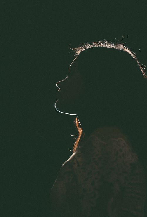Free Ambient silhouette of a woman with long hair in soft lighting, evoking mystery. Stock Photo