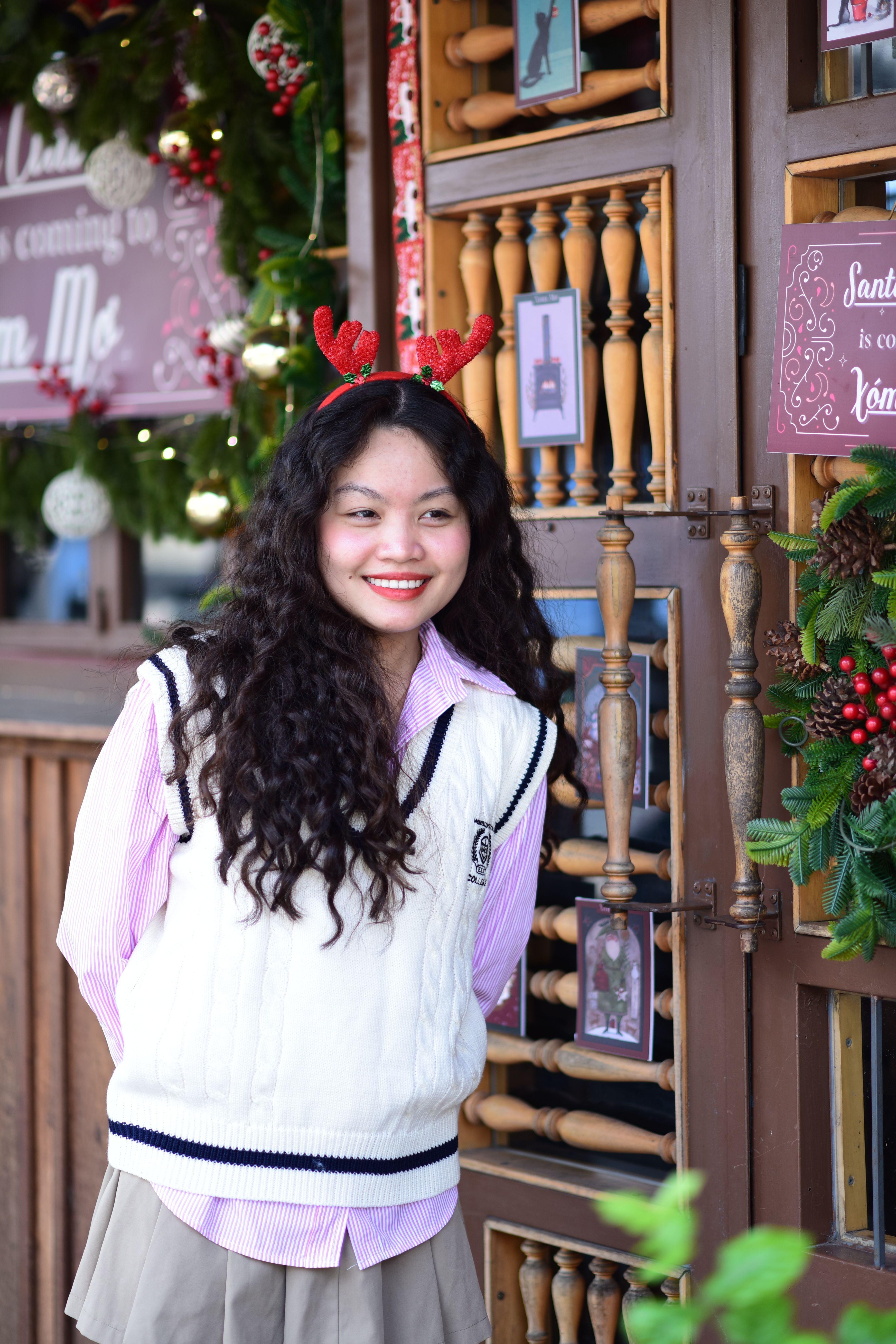 Woman wearing reindeer antlers in festive setting smiles joyfully. Perfect for holiday themes.