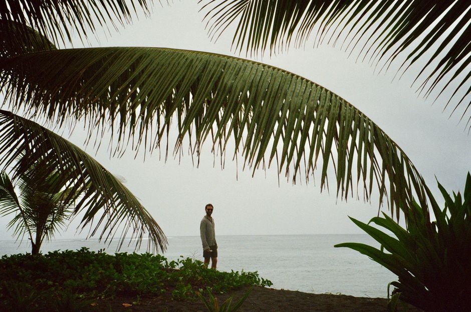A peaceful scene featuring a person on a tropical beach under palm trees in French Polynesia.