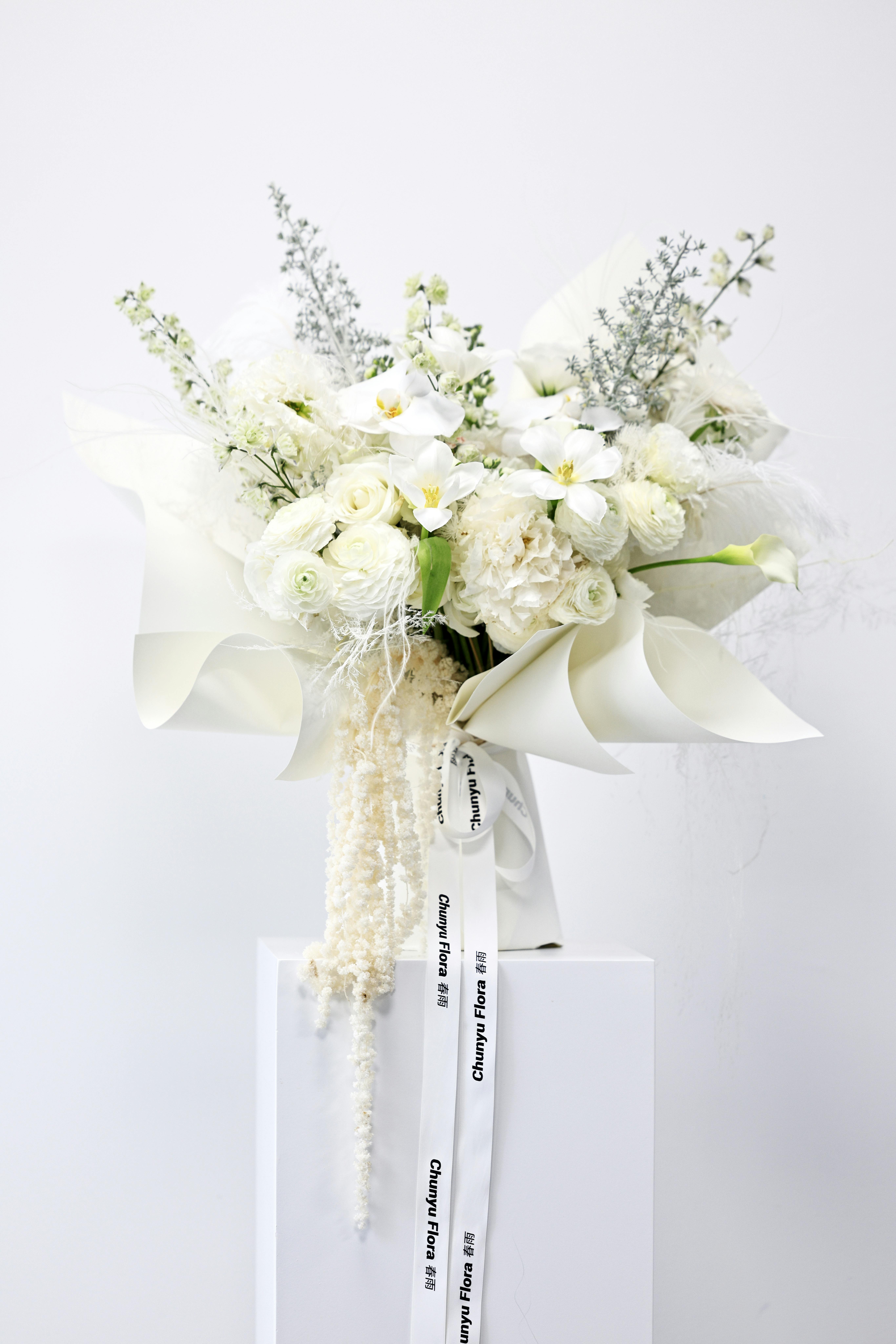 A stunning bouquet of white flowers featuring calla lilies, elegantly arranged in a minimalist style.