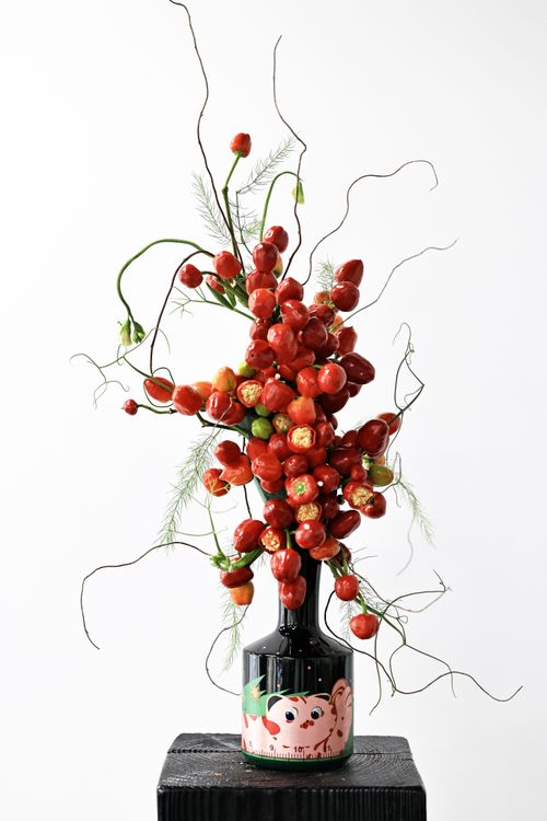 Free Striking arrangement of red flowers and greenery in a unique artistic vase, highlighting creativity and elegance. Stock Photo