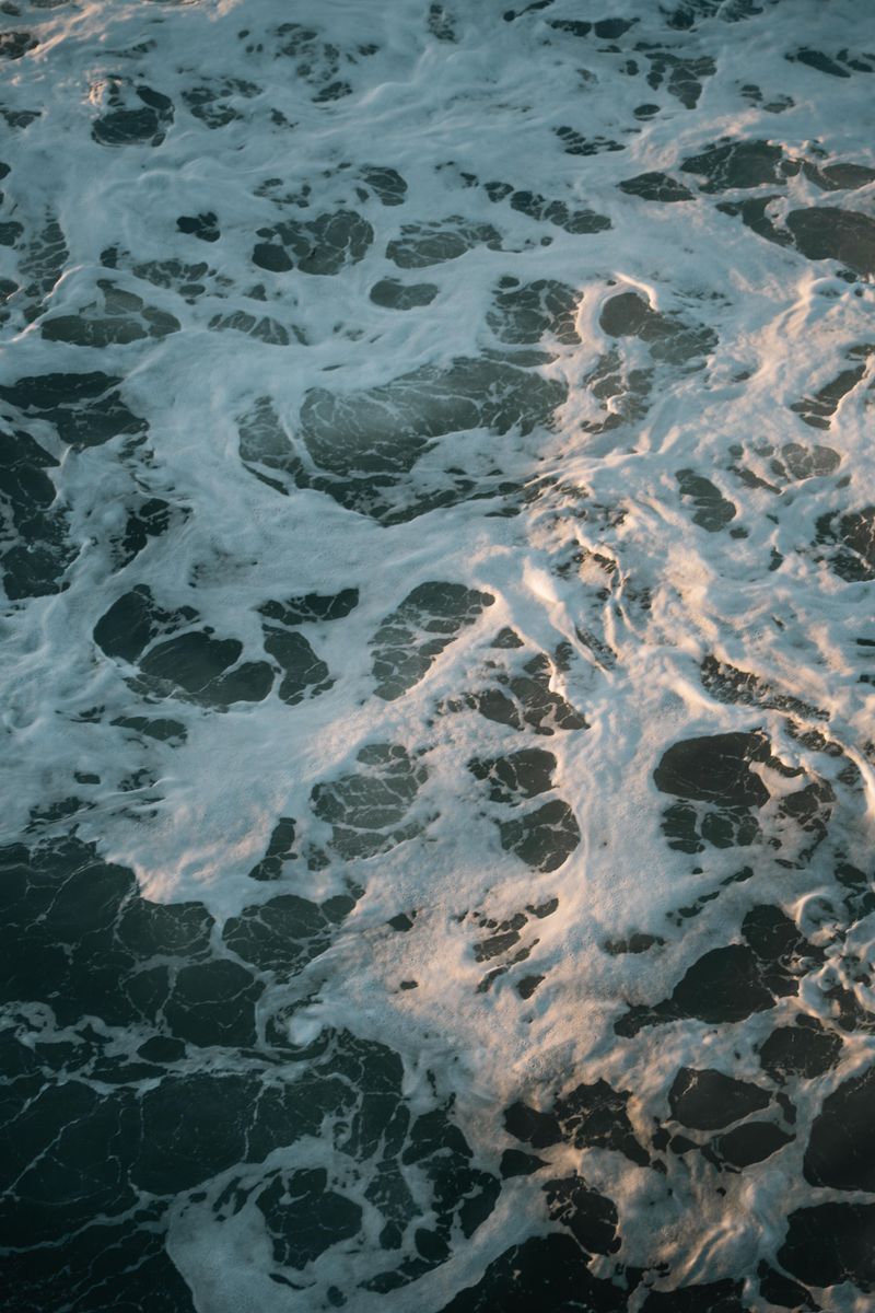 Dramatic aerial shot of ocean waves with white foam creating patterns.