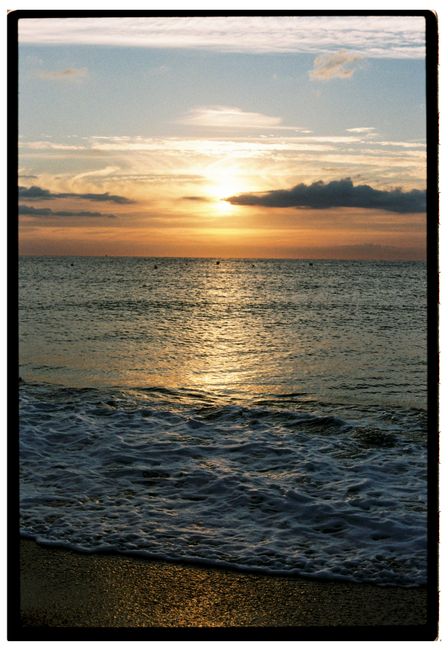 Peaceful beach sunset with waves and clouds, creating a serene ambiance.
