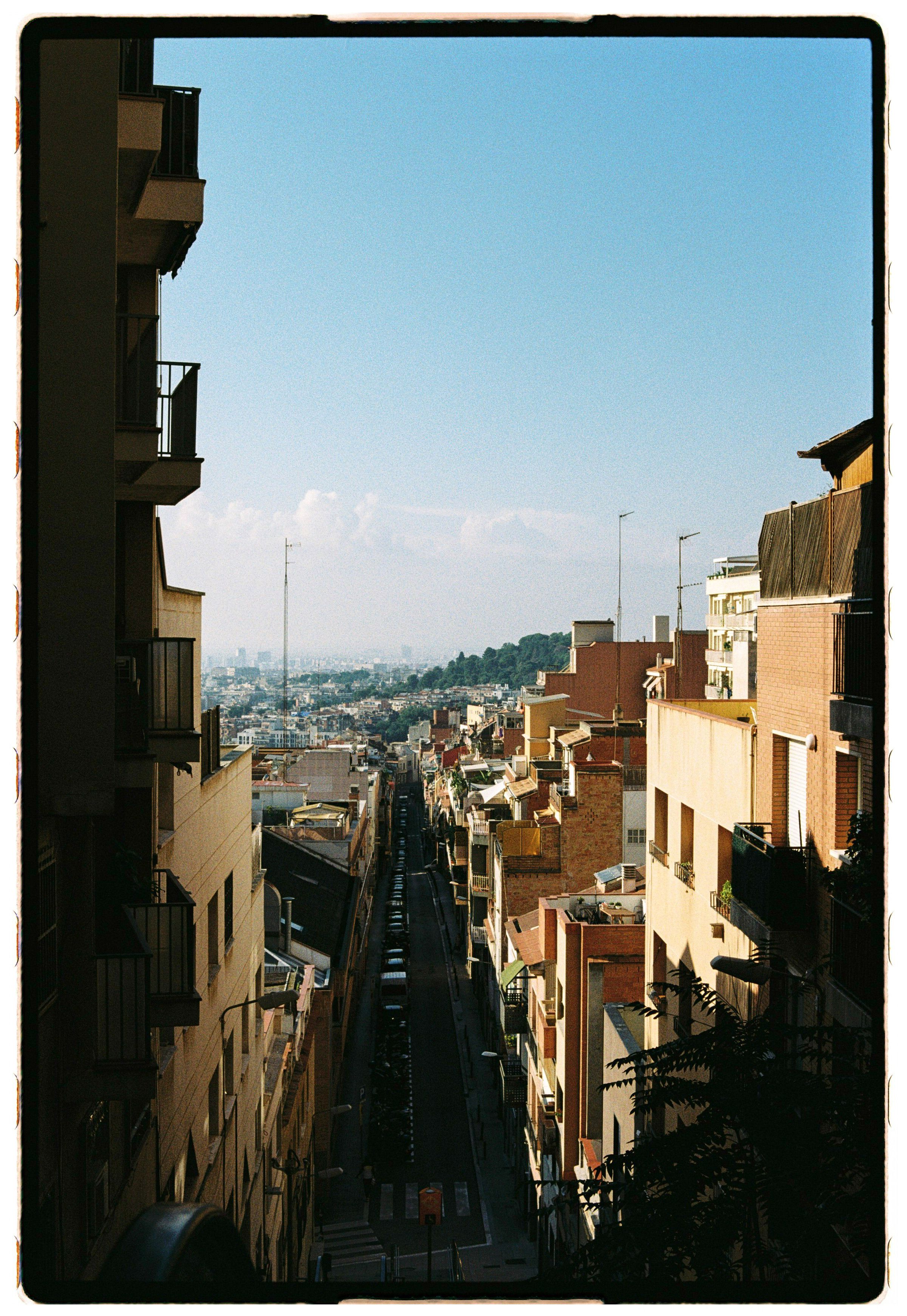 Picturesque urban street view with distant hills and clear blue sky, perfect for travel and cityscape themes.