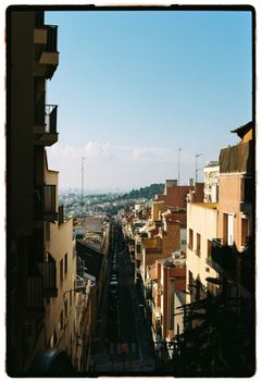Picturesque urban street view with distant hills and clear blue sky, perfect for travel and cityscape themes.