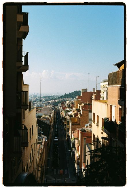Picturesque urban street view with distant hills and clear blue sky, perfect for travel and cityscape themes.