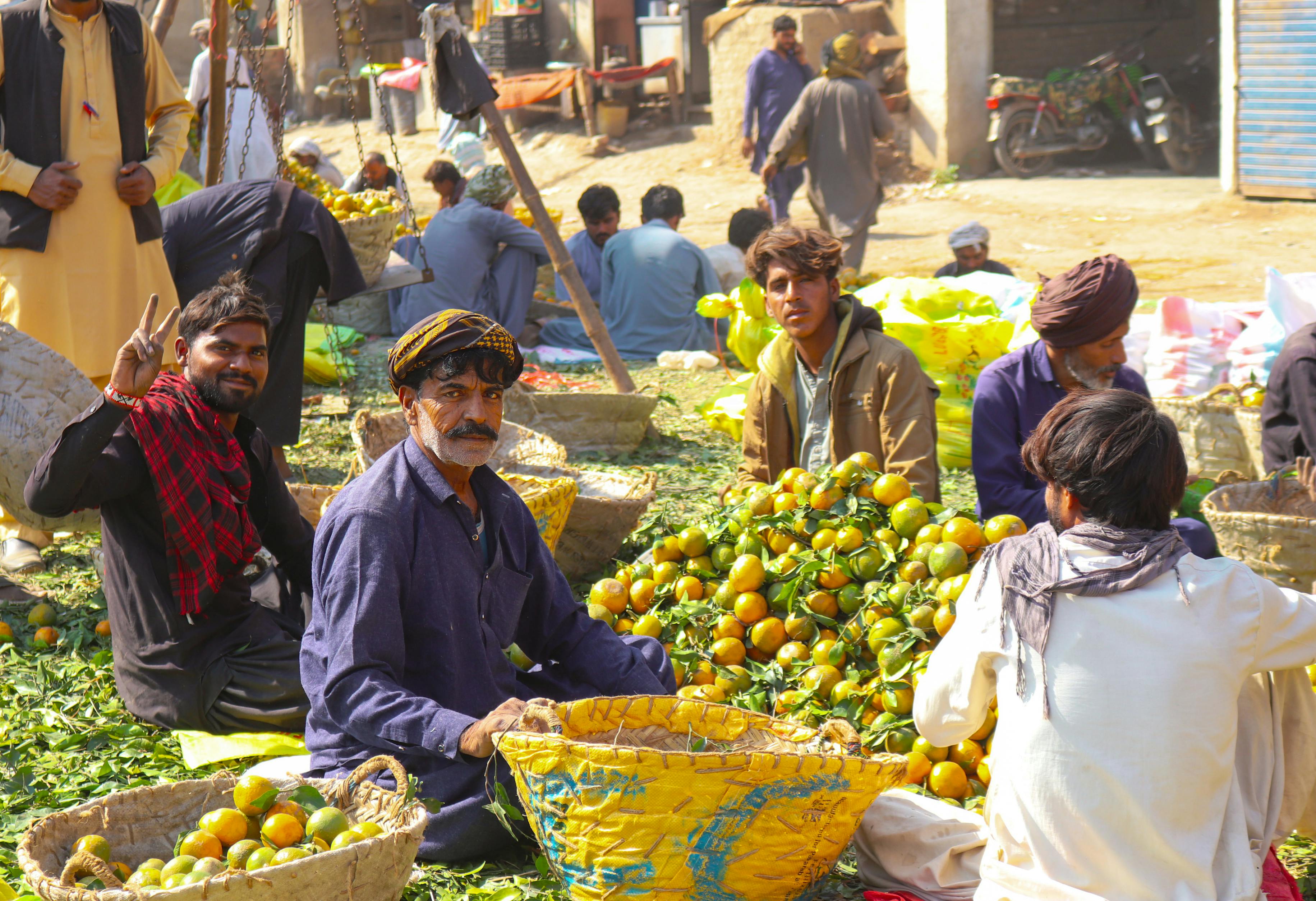 Lively scene of fruit sellers at a bustling market in Sukkur, Pakistan, showcasing local culture.
