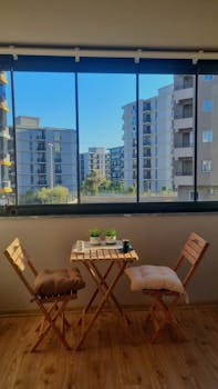 Cozy balcony setup with chairs and table overlooking modern buildings.
