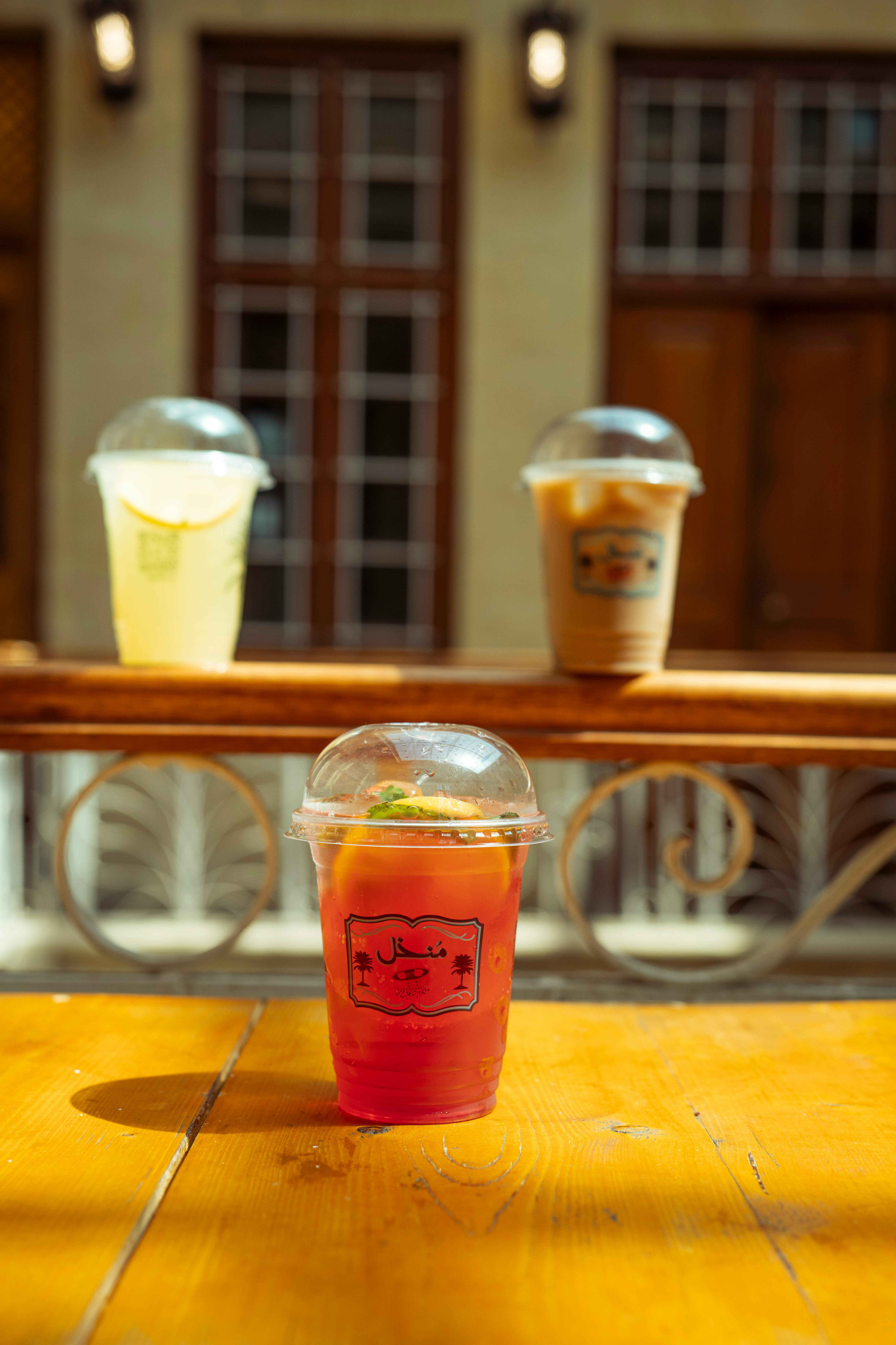 A variety of refreshing drinks on a sunny wooden table in a cozy cafe setting.
