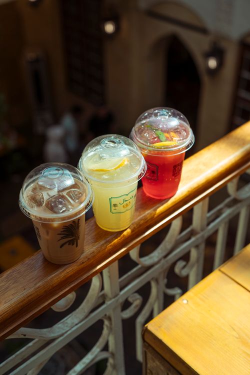 Free Three refreshing iced drinks sit on a sunlit balcony railing indoors. Stock Photo