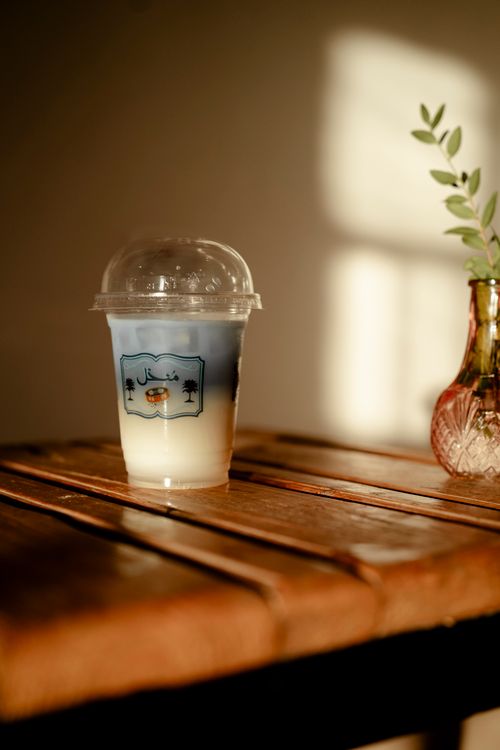 Free Aesthetic cafe setting featuring an iced drink and warm lighting on a rustic table. Stock Photo