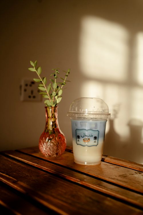 Free Aesthetic iced coffee and decorative vase on a table in warm sunlight. Stock Photo