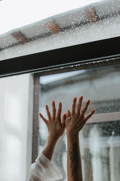 Free Close-up of hands touching a rainy window, conveying emotion and introspection. Stock Photo