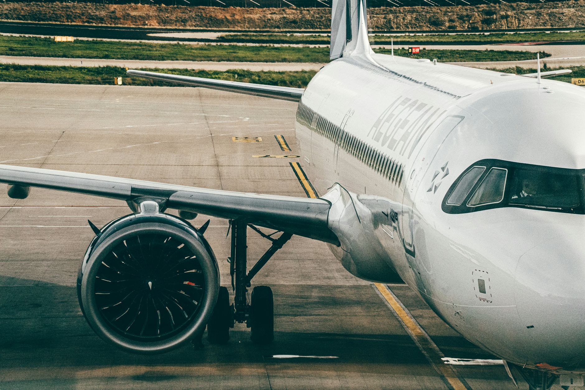 Aegean Airlines airplane parked on airport tarmac, showcasing the aircraft's engine and fuselage.