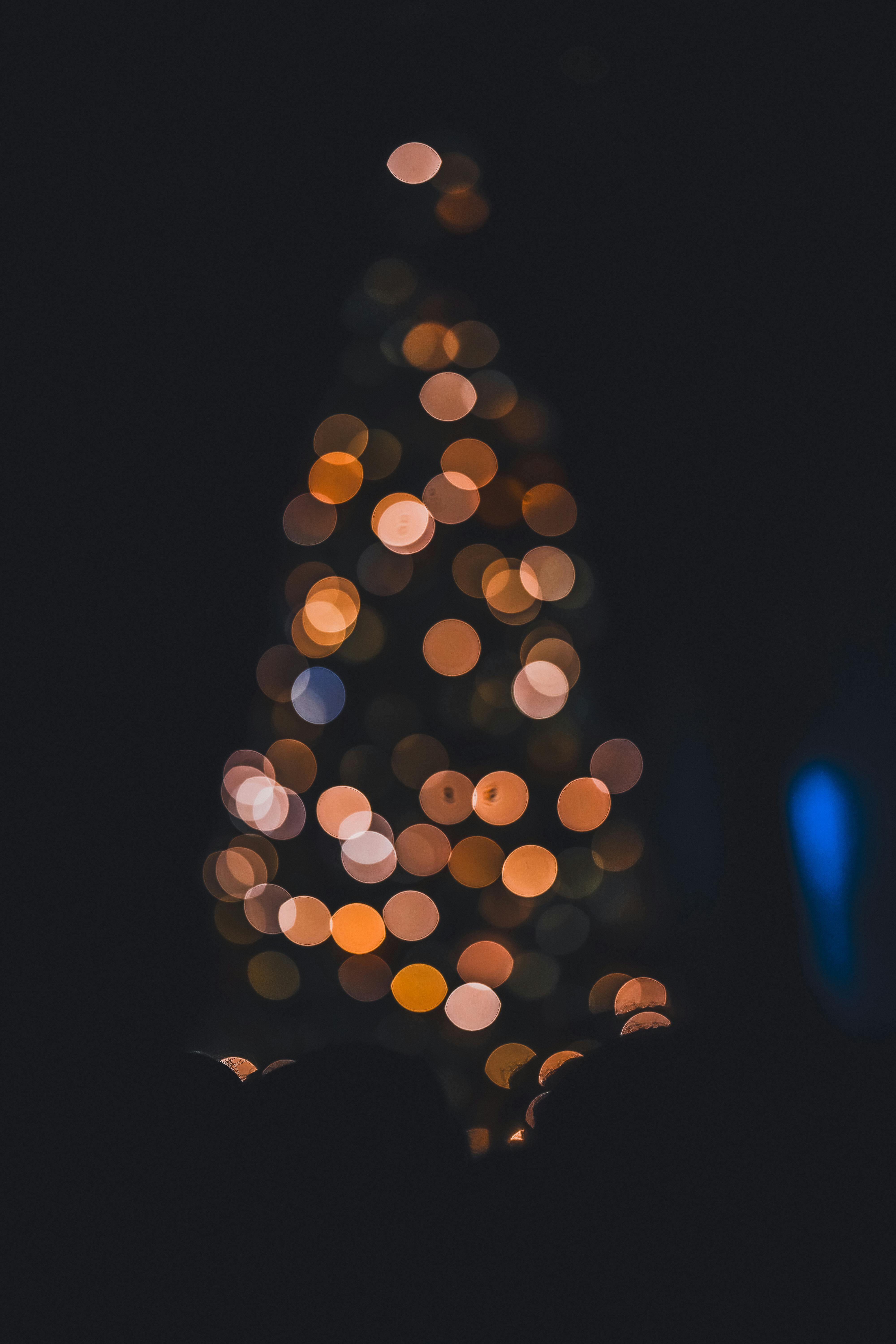 Artistic blurred Christmas tree with colorful bokeh lights in a dark room.