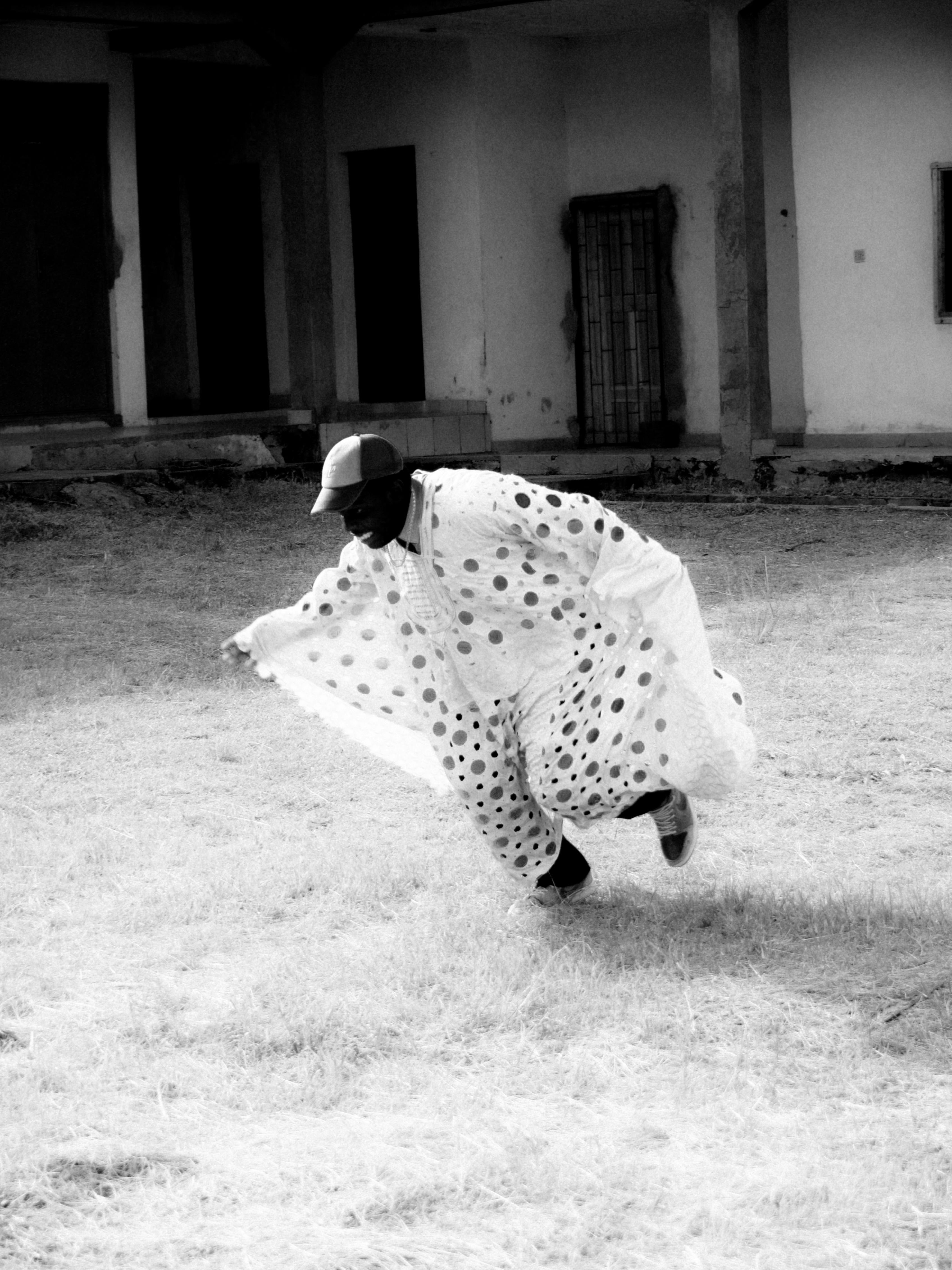 Gratuit Un homme en tenue à pois danse avec énergie en extérieur, en noir et blanc. Photos