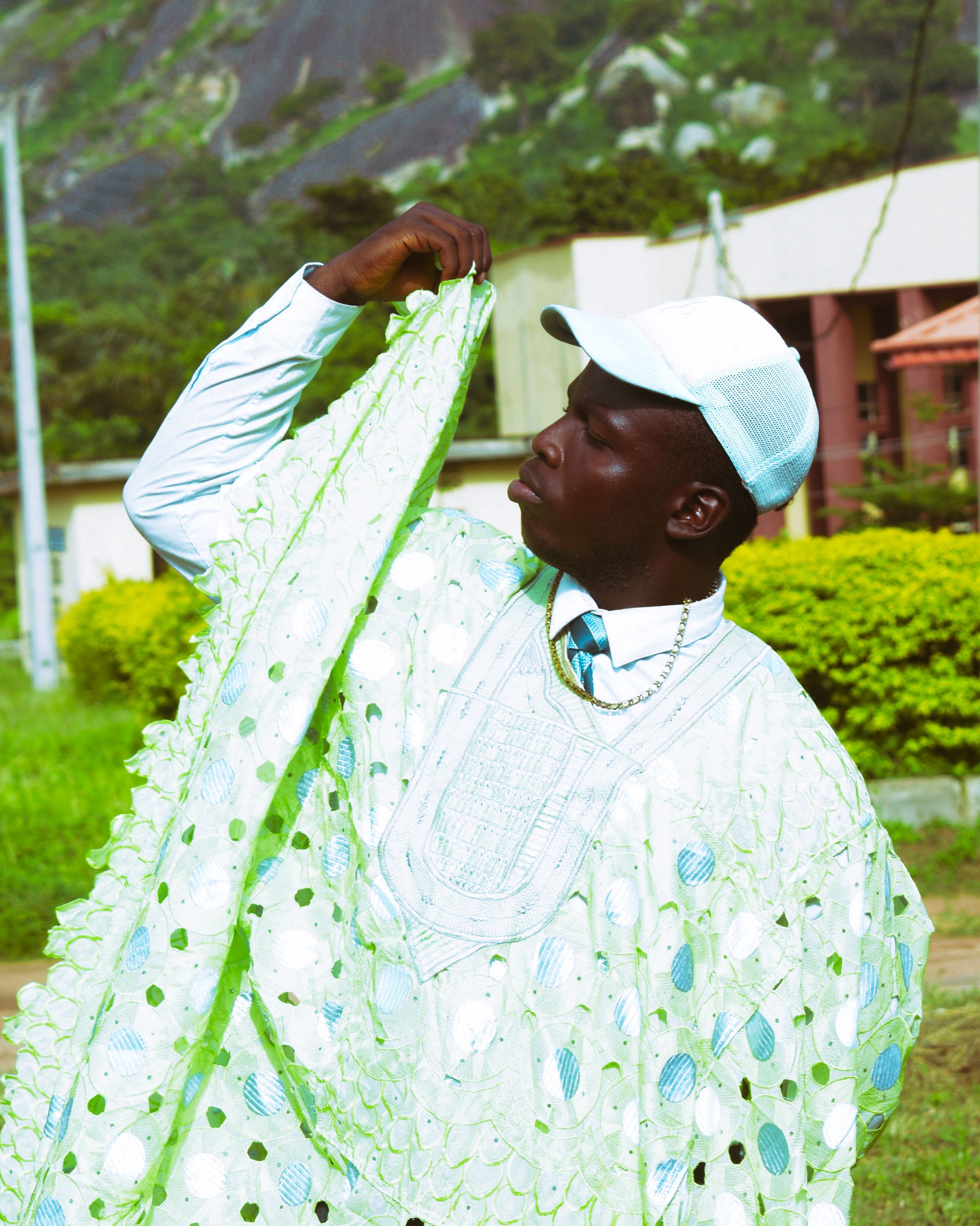 Man posing outdoors in colorful traditional attire, showcasing vibrant fashion.