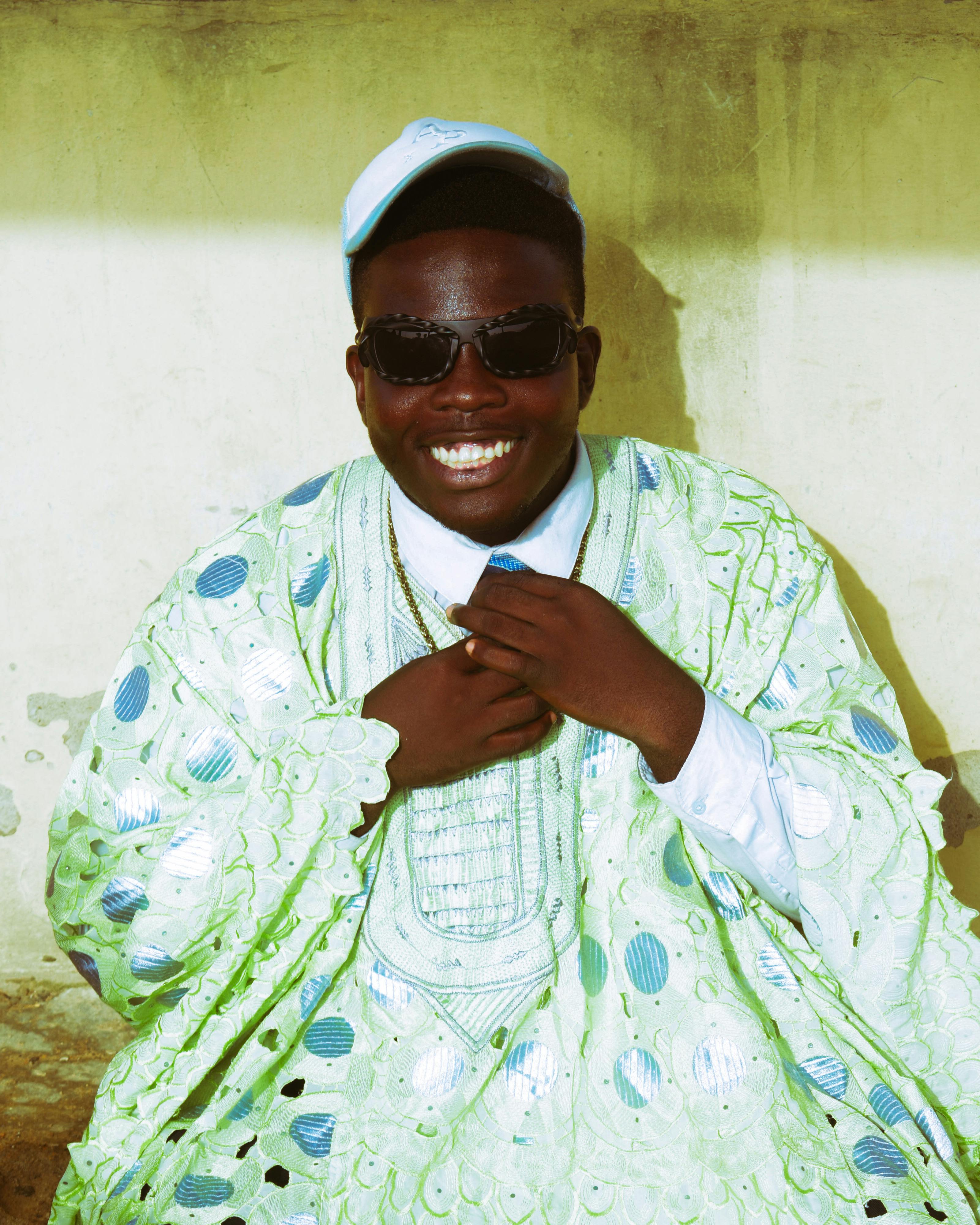 Joyful African man wearing sunglasses and bright traditional clothing outdoors.