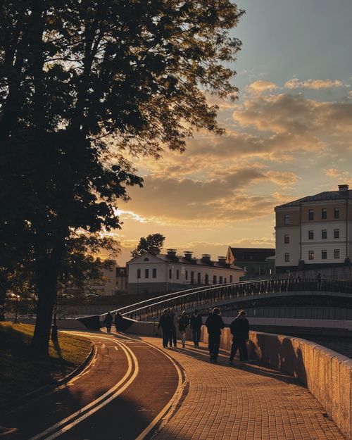 Free People walking on a picturesque bridge walkway at sunset with historical buildings. Stock Photo