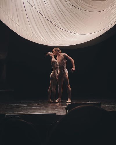 Two dancers lit against a pale disc backdrop, photo by Iryna Varanovich on Pexels