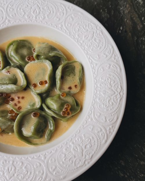 Free Close-up of spinach tortellini in a creamy sauce with decorative plate. Stock Photo
