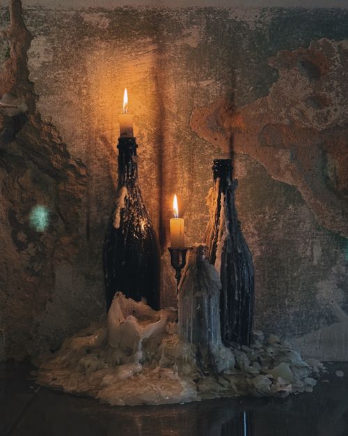 Free Dark and atmospheric still life of candles burning atop wine bottles with dripping wax. Stock Photo
