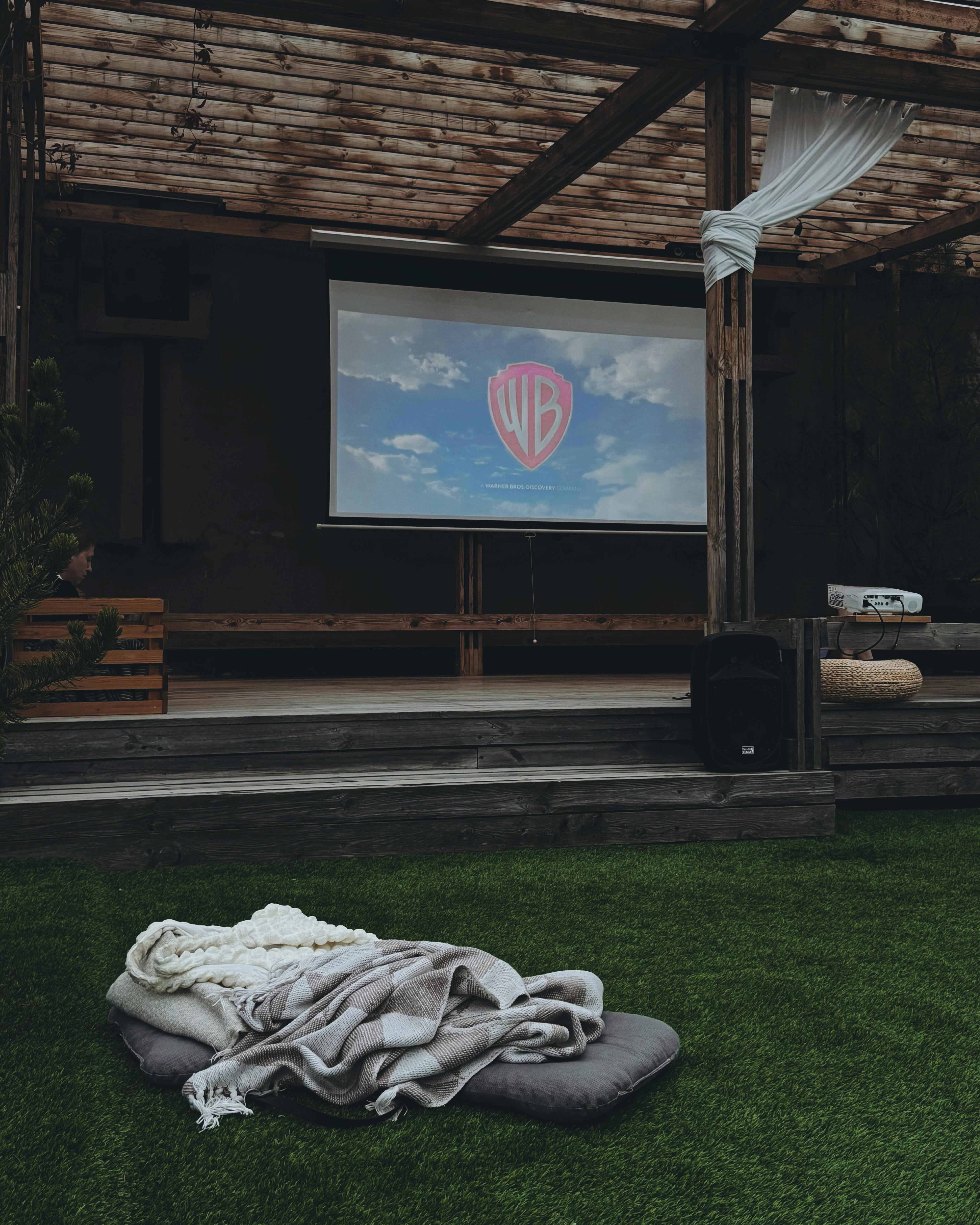 Outdoor cinema with comfy seating and a projector screen for a cozy movie night experience.