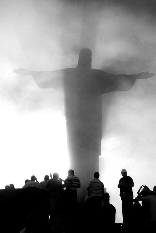 Free A dramatic silhouette of Christ the Redeemer shrouded in mist with onlookers, Rio de Janeiro. Stock Photo